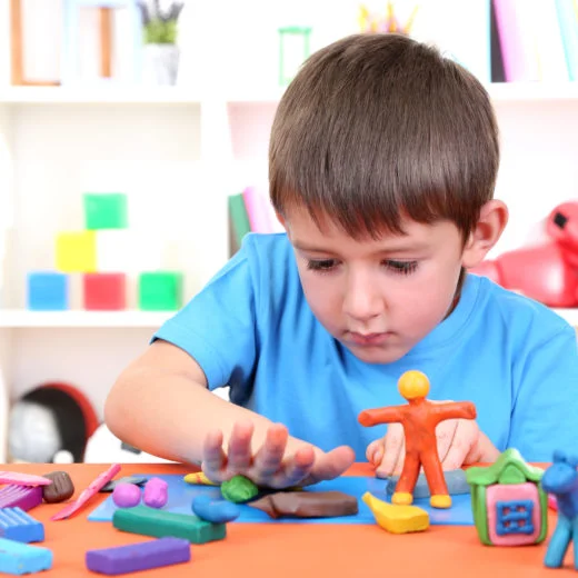 Young boy working on fine motor skills with modelling clay