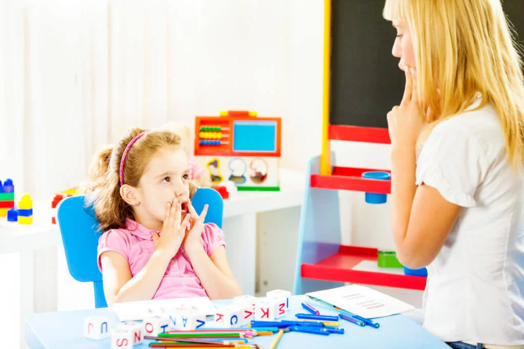 A speech-language pathologist working with a young girl on speech sounds